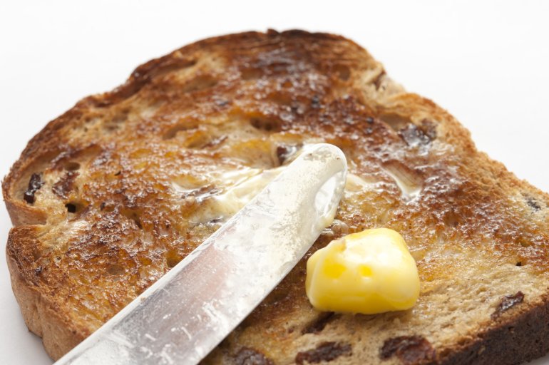 Close-up of slice of bread with raisin,knife and a stick of butter