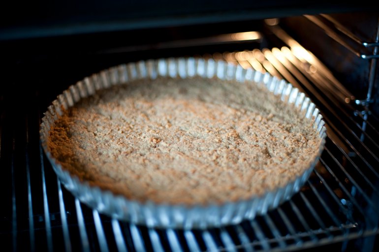 Baking a cheesecake base in a fluted metal pie pan in the oven ready to add the creamy topping and flavouring