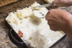 Chef topping a fish pie with mashed potato