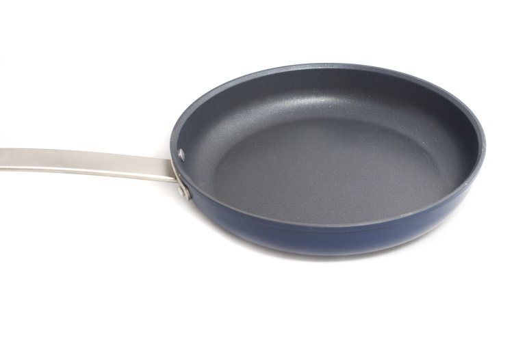 Clean non-stick frying pan with metal handle isolated on white with copy space