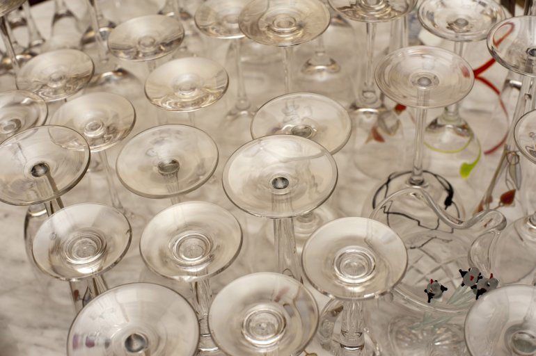 Variety of upended clean glassware with assorted shapes of wineglasses and glasses on a white table in a bar or restaurant