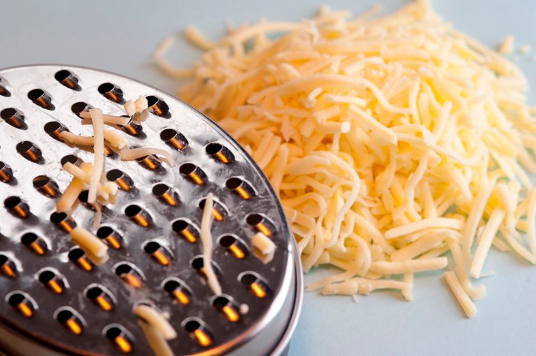 Grating hard cheese using a round metal grater for use as a topping and ingredient for cooking