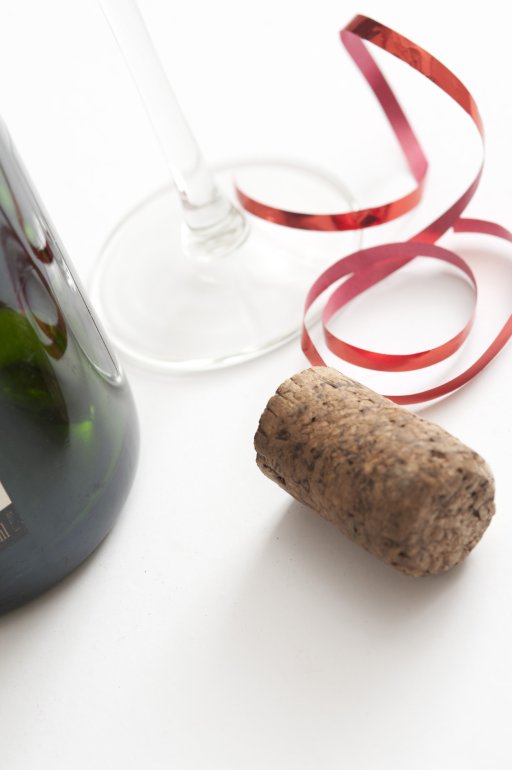 a champagne bottle cork, red ribbons the base of a bottle and glass in frame