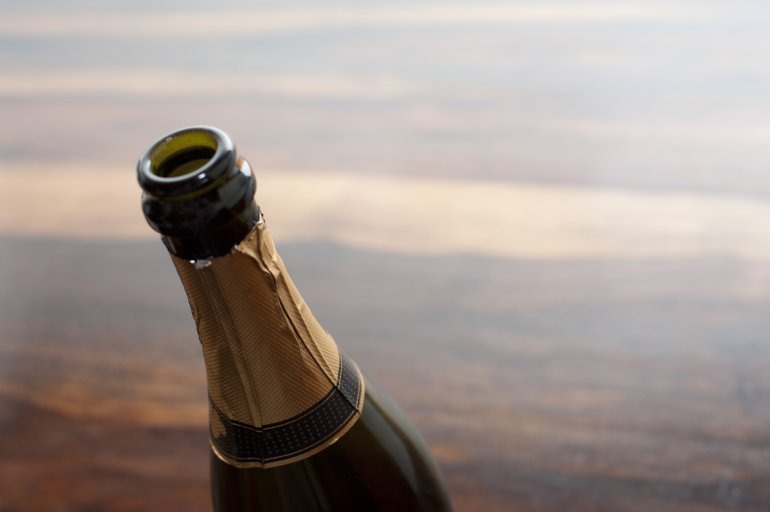 Opened bottle of champagne for a celebration and party against a high key background with copyspace, close up on the neck