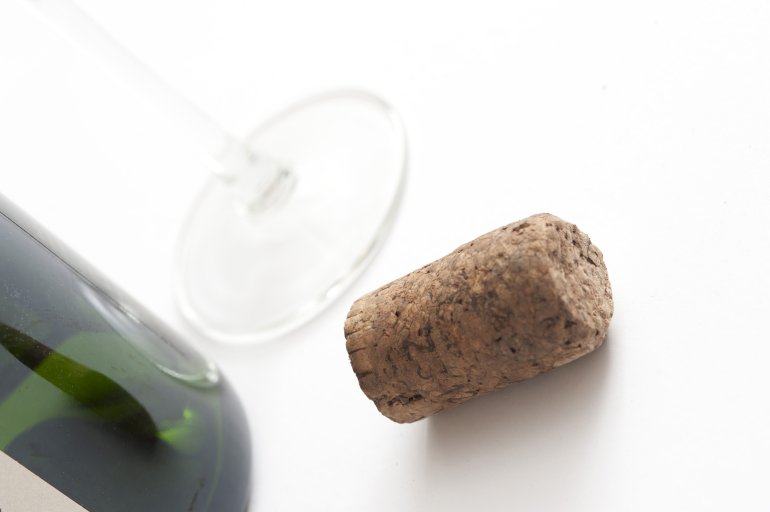 Close Up of Cork Beside Wine Bottle and Glass on White Background in Studio