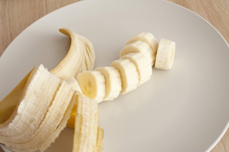 A banana peeled and sliced on light background