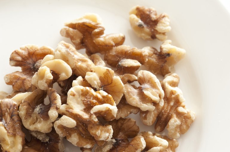 Pile of walnuts on white plate. From above