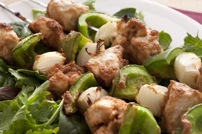 Grilled chicken skewers with green pepper and onions served with a fresh leafy green salad , close up view on three kebabs