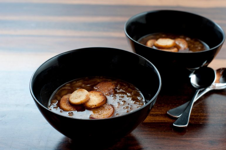 Crisp golden fried bread croutons floating in bowls of tasty brown French onion soup served as a starter or appetizer