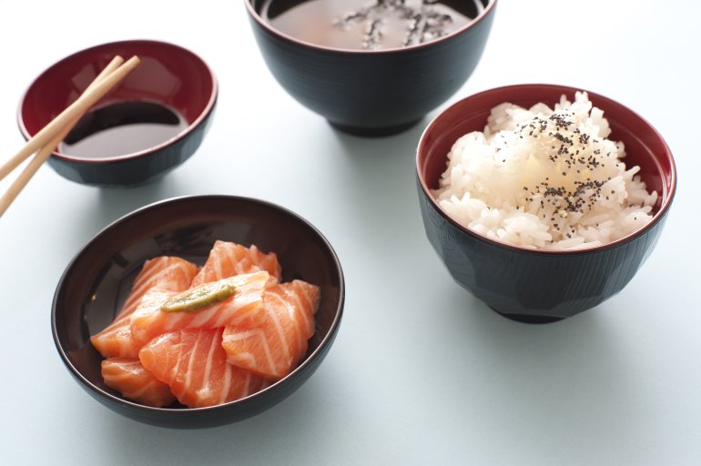 High Angle Culinary Still Life View of Asian Sushi Meal Consisting of Raw Salmon, Rice, Miso Soup and Soy Sauce Served in Bowls with Chopsticks