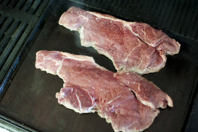 Two joints of beef roasting on grill. From above