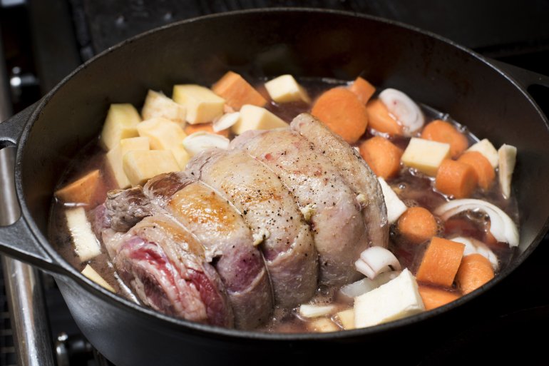 Roast beef joint and vegetables in a casserole pot viewed close up high angle ready to be served for a tasty dinner