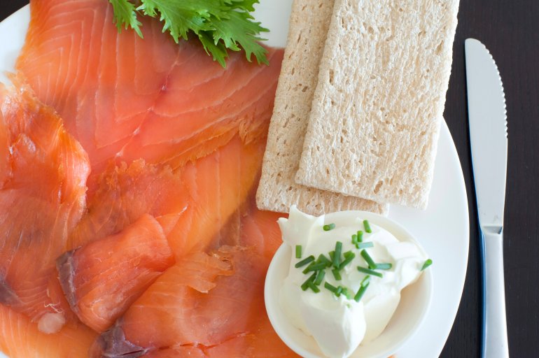 Gravalax, or thinly sliced cured and smoked salmon, with cream cheese and crispbread, close up overhead view