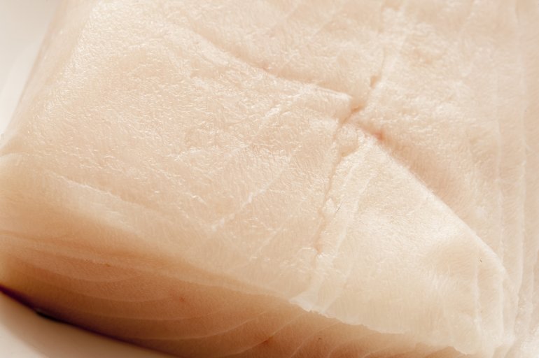 Cropped close up view on cut of raw mackerel fish meat with lines and slightly dry surface