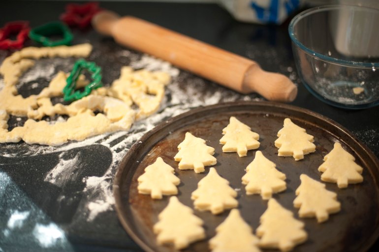 Baking homemade Christmas cookies with pastry cut out in the shape of traditional Christmas trees arranged on a baking tray to go into the oven