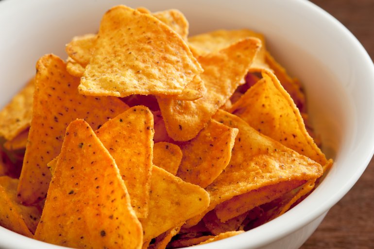 Bowl of traditional triangular corn tortilla chips or nachos for a delicious dipping snack or appetizer in a close up view