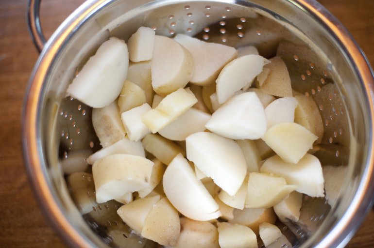 Chopped potatoes in colander Chopped white potatoes in colander viewed from above in close-up