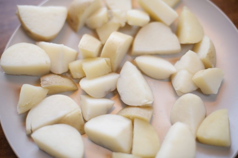 Cut potatoes on a plate Cut fresh potatoes on white plate in close-up from above