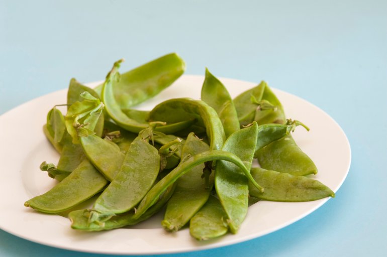 Plate of fresh sugar snap peas with their crisp green edible pods used as a salad ingredient in cookery
