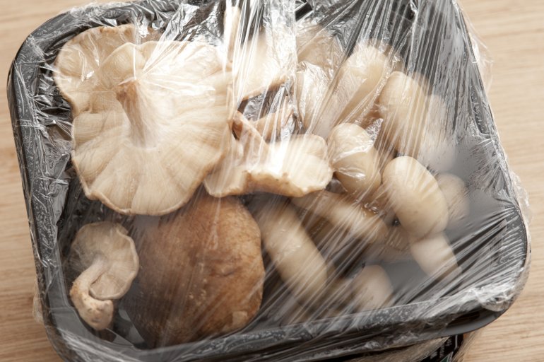 Prepacked mushrooms in a punnet covered with clear plastic including fresh whole Japanese shitake and shimeji mushrooms