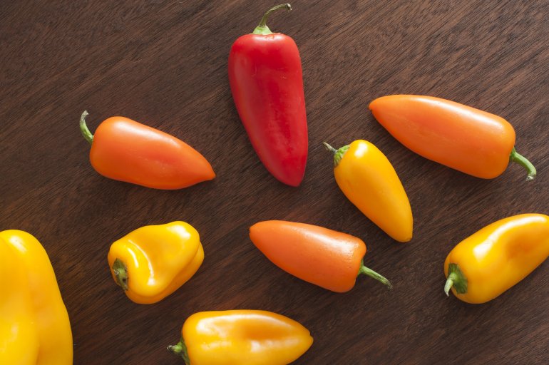 Whole red and yellow peppers Whole red and yellow peppers on dark brown wooden background, viewed from above