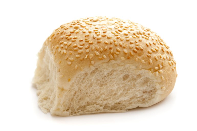Freshly baked sesame roll with a crispy crust covered in sesame seeds over a white background, side view