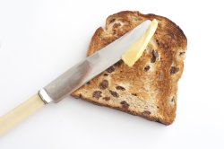 Spreading butter on a slice of toast