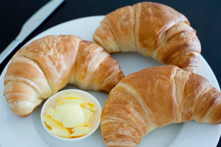 Crispy croissants and butter Crispy freshly baked golden croissants and butter served on a plate for a delicious breakfast or snack