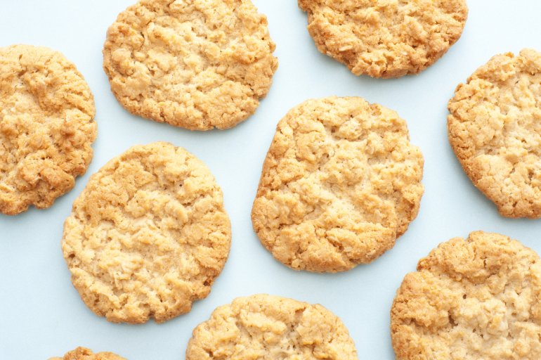 fresh golden oatmeal cookies Background of fresh golden oatmeal cookies scattered on a white surface viewed from overhead in a full frame view