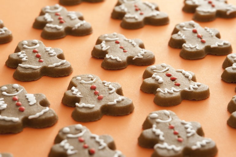 Pattern of festive gingerbread men decorated with icing sugar on an orange background in a low angle view with selective focus