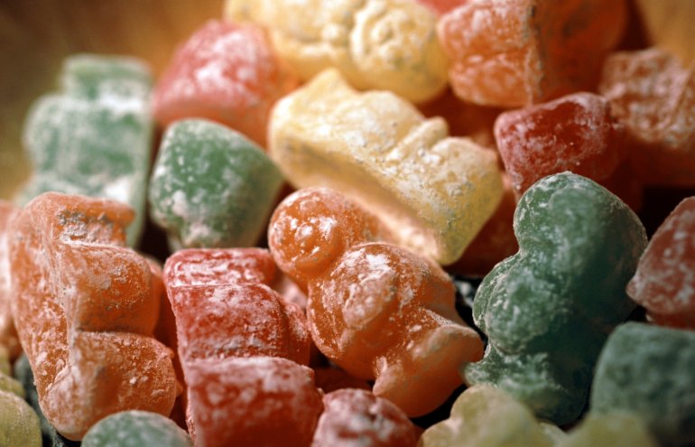 Background of colourful jellybabies candy in assorted colours with focus to two orange and green sweets