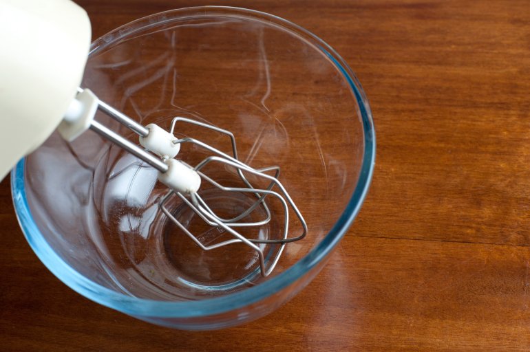 High angle view of an electrical mixer in the kitchen with the whisk attachment resting in a clear glass bowl