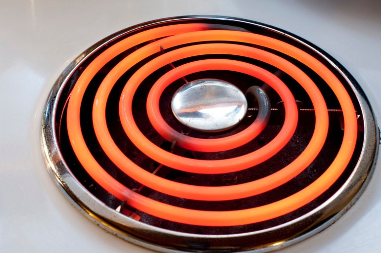 Red hot spiral electric hotplate on a stove top in a domestic kitchen for cooking food