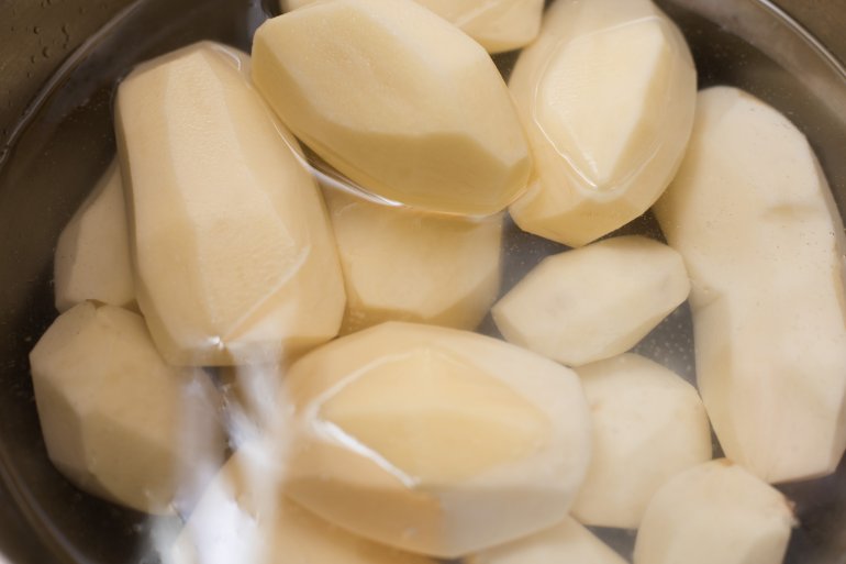 Peeled potatoes in water ready for cooking Peeled potatoes standing in a pot water ready for cooking in a close up high angle view