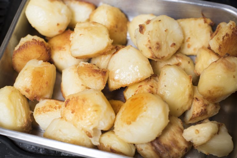 roasting tin of fresh roast potatoes Metal container of golden crispy fresh roast potatoes on a buffet , close up high angle view