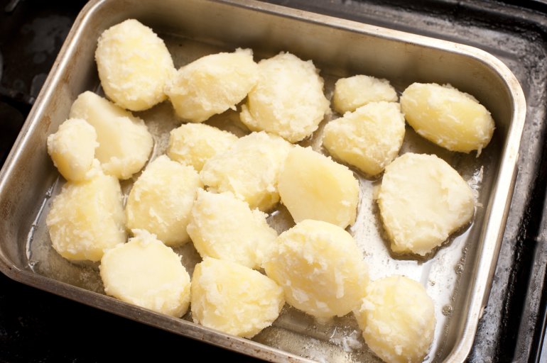 Par boiled potatoes ready for roasting Par boiled halved potatoes ready for roasting in a baking tray viewed from above