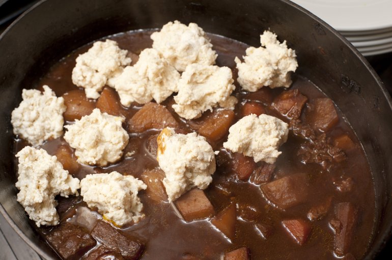 Raw dumplings in a rich beef stew Raw dumplings in a rich beef stew waiting to be cooked for dinner , close up high angle view into the pot