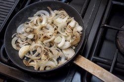 Fresh sliced white onions frying in a pan