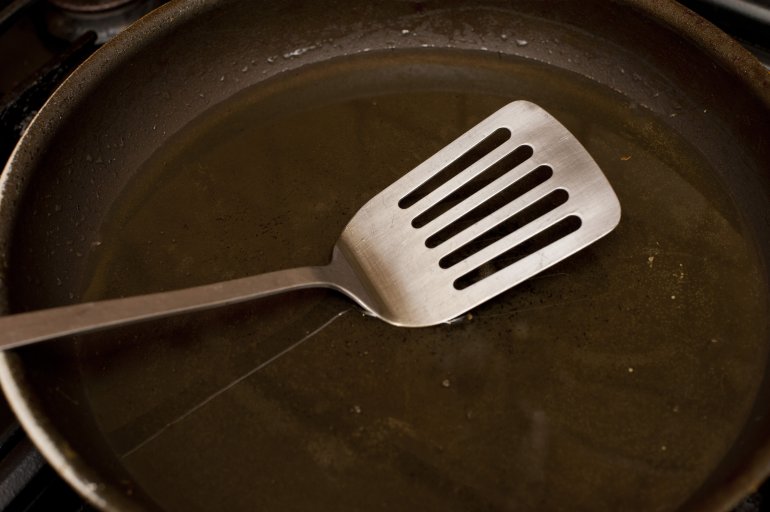 Clean non-stick frying pan with metal spatula Clean non-stick frying pan with metal spatula in a close up view in a food cooking concept