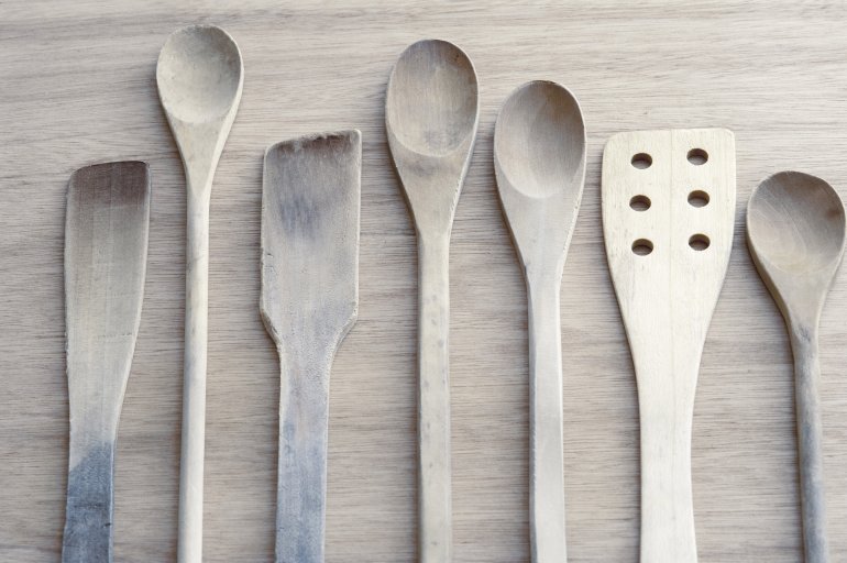 Toned grey neutral set of wooden kitchen utensils neatly laid out in a row with spoons and spatulas