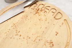 Wooden bread board and knife with crumbs