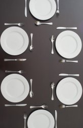 Dark table set with clean white plates and cutlery