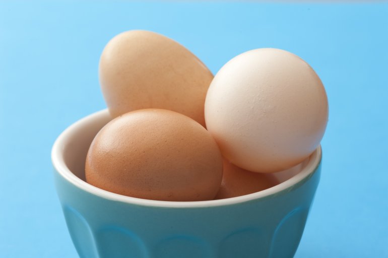 Little blue bowl of brown eggs over matching color background for concept about farm fresh food