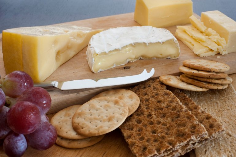 Selection of cheese on a cheeseboard on a buffet served as an appetizer with water biscuits and wheat crackers