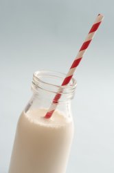 Full glass bottle of milk with a straw