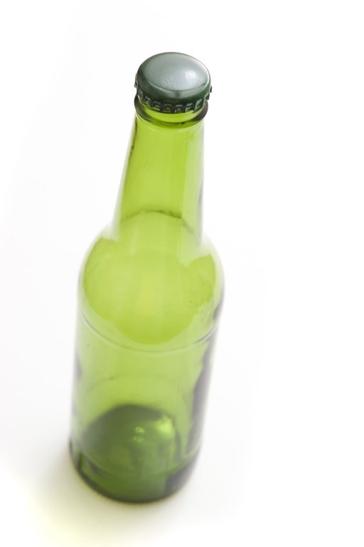 Unlabelled capped green beer bottle on a white background, high angle view