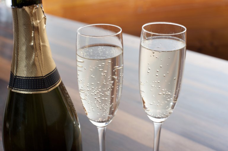 Two elegant flutes of sparkling champagne Two elegant flutes of sparkling champagne alongside a champagne bottle to celebrate a special occasion or romantic tryst