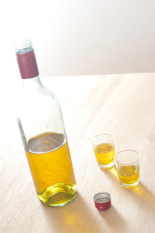 Bottle and Glasses of Yellow Wine on Table Close up Unlabled Bottle and Glasses of Yellow Wine on Top of a Wooden Table