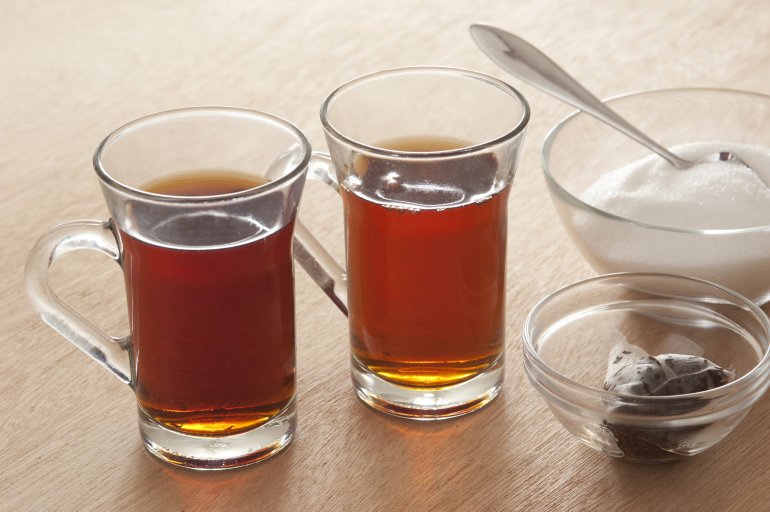 Hot black tea for two Hot black tea for two served in glass mugs with a bowl of sugar and the used teabags in a small dish