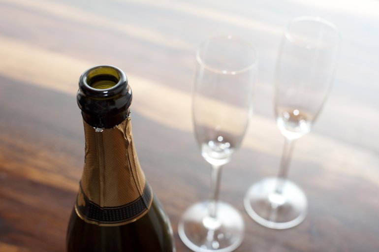 Opened champagne Opened champagne with a close up view of the neck of the de-corked bottle with two empty elegant flutes alongside for a romantic celebration